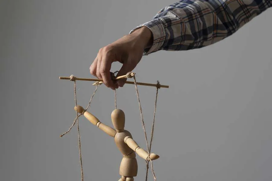 Hand manipulating wooden marionette on strings — regaining control over balance