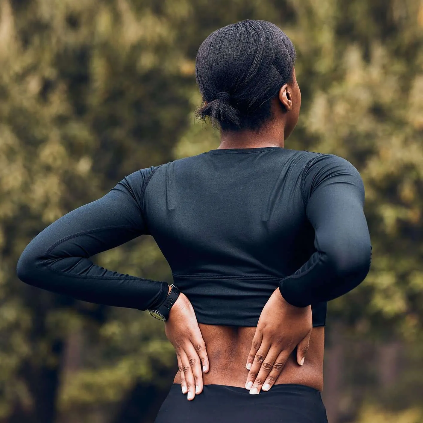 Woman experiencing back pain during outdoor exercise